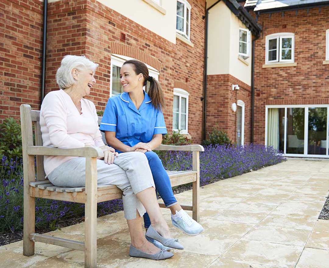 A caregiver gently helping an older adult review their medication record together on a tablet.